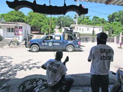 Miembros del nuevo grupo de Policía Comunitaria observan una patrulla de la Policía Federal que pasa frente a ellos en Aquila. AFP /