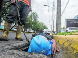 Cuadrilla de desazolve. Trabajadores del SIAPA limpian una alcantarilla colmada de desechos humanos. EL INFORMADOR /