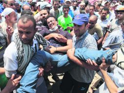 Seguidores de los Hermanos Musulmanes cargan a uno de sus compañeros lesionados al enfrentarse a la Policía el sábado pasado. AP /