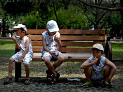 Ajenos a la contaminación, tres niños comen fruta en un parque de Beijing. AP /