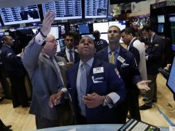 Especialistas de EU consultan las cifras tras iniciar la jornada en la bolsa de la Gran Manzana. AP /