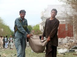 Oficiales afganos retiran un cuerpo del sitio dónde los extremistas hicieron estallar el auto. AP /