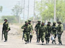 Algunos militares caminan rumbo a su puesto de control en la entrada de Tepalcatepec. AFP /