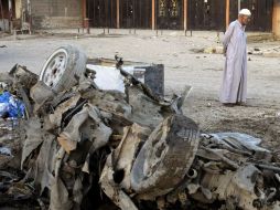 Un hombre camina frente a un coche que explotó durante una ola de ataques suscitados hoy. EFE /