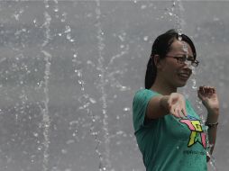 Una mujer se moja para refrescarse ante las temperaturas de hasta 40 grados que sacuden a China. AP /