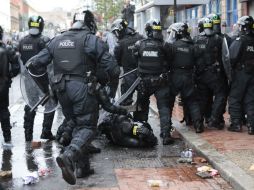 Un policía cae tras ser golpeado con un ladrillo. AP /