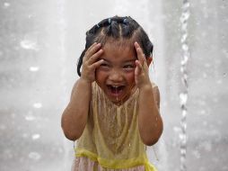 Una niña se refresca en una fuente pública de Tokio. AFP /