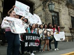 Algunos de miembros del club de fans ''Rushers de Jalisco'', sostienen pancartas en las afueras del Palacio de Gobierno.  /