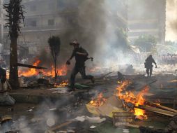 Dos reporteros corren buscando cubrirse de los enfrentamientos entre los seguidores y opositores de Morsi. AFP /