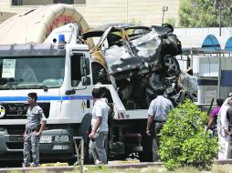 Varias personas observan uno de los coches de la Policía que fueron destrozados tras los atentados con coches-bomba en Bagdad. EFE /