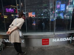 Una mujer observa a través de una ventana las pantallas en negro del índice Nasdaq. AFP /