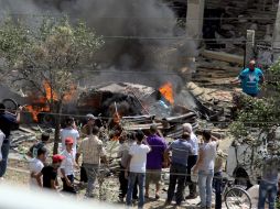 Ciudadanos observan uno de los autos que estalló. AFP /
