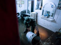 Un elemento del Ejército saca el agua de un comercio en el municipio de Zapopan, castigado ayer por una fuerte lluvia.  /