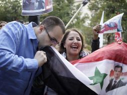 Un simpatizante del régimen besa una bandera siria con la imagen del presidente sirio. AFP /