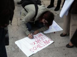 Una manifestante escribe en una cartulina que usará como pancarta durante las marchas. NTX /