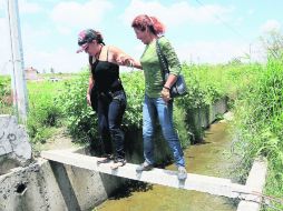 Tlajomulco de Zúñiga. Esperanza y María, vecinas de Lomas del Sur, intentan cruzar el canal de aguas negras a cielo abierto.  /