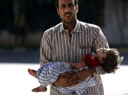 Un hombre sirio coge a su hija herida por una bomba mientras espera para cruzar la frontera. EFE /