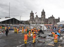Empleados de limpia capitalinos levantan los restos del plantón del CNTE. AP /
