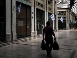 Un hombre pasa junto a un centro comercial donde la mayoría de las tiendas están cerradas en Atenas. EFE /