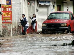 Residentes de Chilpancingo intentan cruzar una calle inundada. AFP /