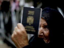 Una mujer muestra su pasaporte mientras espera para cruzar el paso fronterizo con Gaza. ARCHIVO /