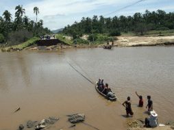 Un grupo de personas cruzan un río cerca del puente derrumbado en Coyuca de Benítez, Guerrero. AFP /
