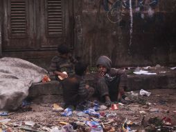 Dos niños sirios mendigos se sientan entre la basura buscando alimentos en Alepo. EFE /