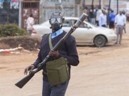 Un policía antimotines evita que la gente se acerque a la zona del tiroteo. AFP /