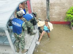 Marinos ayudan a una mujer a subirse a un vehículo oficial, tras quedar inundada la calle donde está situada su vivienda, en Acapulco. AFP /