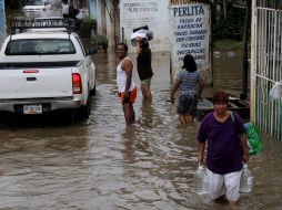 Un grupo de personas carga provisiones en una zona inundada en Guerrero, otro estado afectado por las lluvias. EFE /