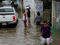 Un grupo de personas carga provisiones en una zona inundada en Acapulco. EFE /