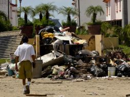 Un hombre en Acapulco pasa por los objetos que quedaron inservibles tras las inundaciones por el paso de dos meteoros. SUN /