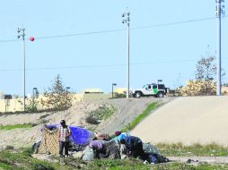 Inmigrantes montan un campamento en la canalización de Río Tijuana. Al fondo, los vigila la Patrulla Fronteriza. NTX /