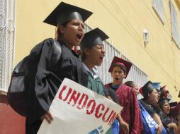 Vestidos con togas de graduación, los jóvenes piden regresar a las comunidades en las que crecieron en EU. AP /
