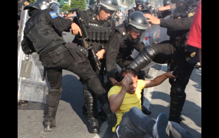 Jóvenes encapuchados se enfrentan a policías en el transcurso de la marcha. SUN /