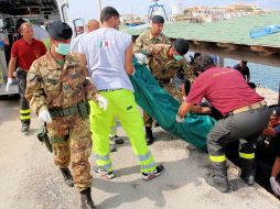 Personas trasladan el cuerpo de uno de los 94 inmigrantes muertos, tras el naufragio en la isla de Lampedusa. EFE /