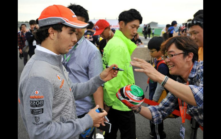 'Checo' ofrece algunos autógrafos a sus admiradores dentro del circuito de Corea. AFP /