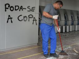 Un empleado limpia los restos de vidrios que fueron destrozados por los manifestantes. AFP /