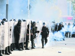 Policías capitalinos preparan bombas de gas lacrimógeno para contener a los manifestantes en las cercanías del Zócalo capitalino. AFP /