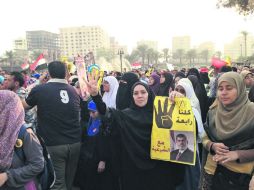 Una mujer porta un retrato de Mohamed Morsi y hace la señal de cuatro dedos levantados, que hace referencia a la plaza de los acampados  /