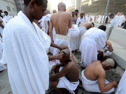 Peregrinos se afeitan la cabeza tras llevar a cabo el apedreamiento de tres columnas que representan las tentaciones del diablo. EFE /