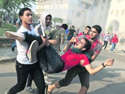 Jóvenes trasladan a un herido luego de que la Policía disparara gases lacrimógenos contra estudiantes islamitas AFP /