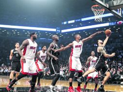 Hasta la cocina. Deron Williams realiza un tiro bajo la canasta, ante la marca de Chris Bosh. EFE /