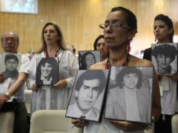 Familiares víctimas sostienen fotografías durante una audiencia sobre el caso de la toma del Palacio de Justicia de Bogotá. EFE /
