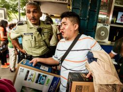 Un ciudadano de Caracas compra electrodomésticos a precios bajos, detrás de él un policía vigila el orden en el establecimiento. EFE /