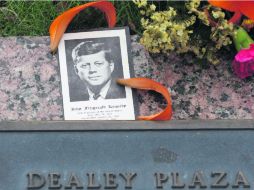Una foto de JKF y flores yacen en una placa en la Plaza Dealey, en Dallas. AP /