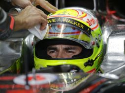 Un miembro del equipo McLaren limpia el casco de Sergio Pérez antes de correr en la segunda fase de clasificación. AP /