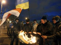 Manifestantes se calientan junto a una hoguera mientran construyen barricadas en la plaza de la independencia en Kiev. EFE /