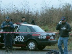 Agentes de la Policía Estatal acordonan el área donde fueron encontrados los cuerpos de tres personas. EFE /