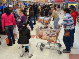 Personas hacen filas para pagar sus compras para la cena.  /